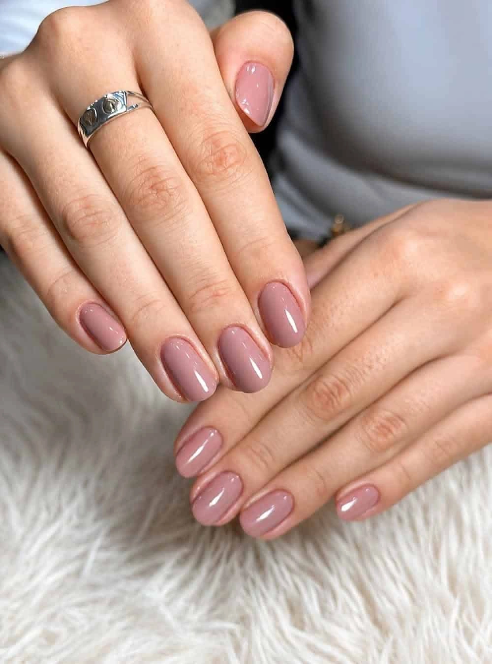 Серо-розовая дымка на овалах Серо-розовый глянцевый маникюр на коротких овальных ногтях обеих рук и серебряное кольцо