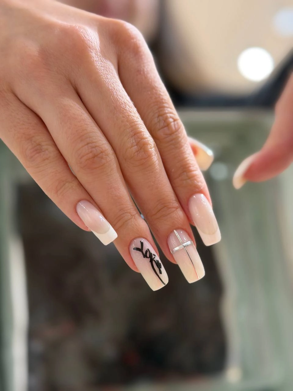 Френч із розчерком Довгі квадратні нігті з молочною базою, білим френчем, чорним рукописним розчерком і срібними смужками